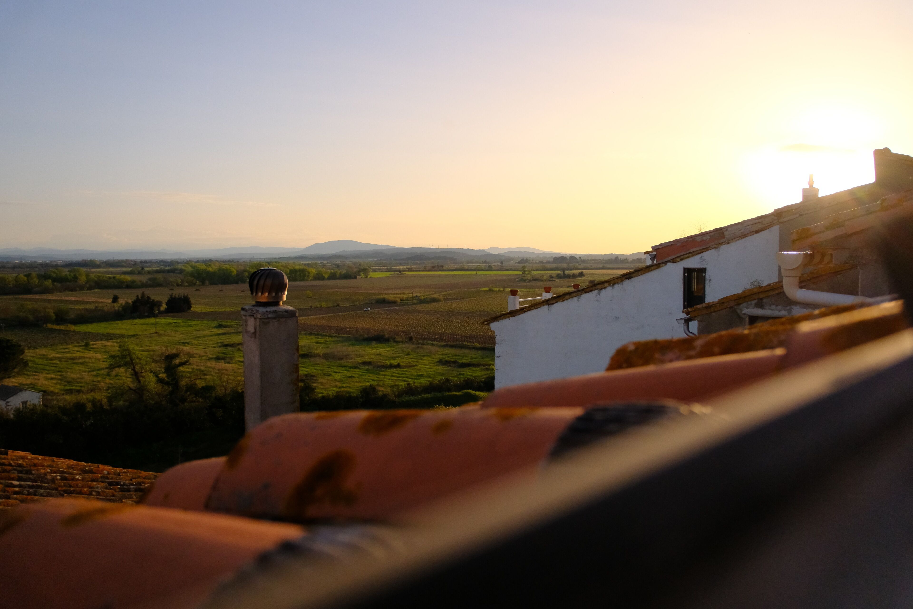 A view from a rooftop terrace overlooking a rural landscape with fields and distant hills.