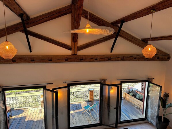 Una habitación con techo de madera, tres ventanas amplias y lámparas colgantes.