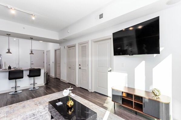 A modern living room with a TV, bar stools, and a coffee table.