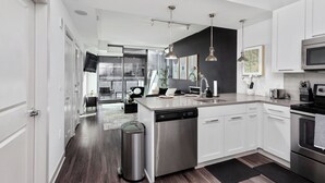 A modern kitchen with white cabinetry, stainless steel appliances, and pendant lighting. - Lux Noir ATL High-rise self check-in Balcony views (Atlanta)