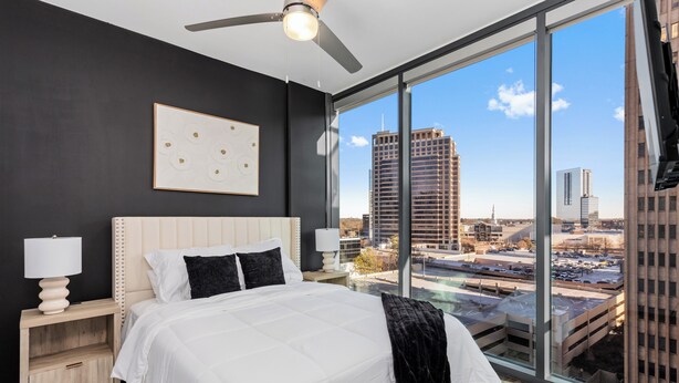 A modern bedroom with a large bed, a ceiling fan, and a city view through large windows. - Lux Noir ATL High-rise self check-in Balcony views (Atlanta)