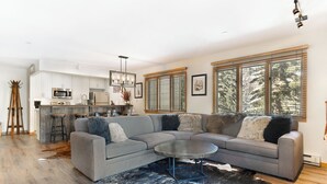 A modern living room with a sectional sofa, a round coffee table, and a black and white cowhide rug. - Mountain Modern Ski In-Ski Out Condo With Hot Tub In Beaver Creek - 1BR/2BA (Beaver Creek)
