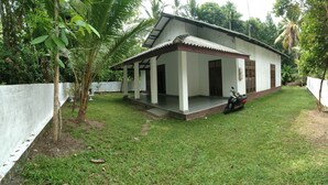 Ein eingeschossiges Haus mit Veranda, umgeben von einem weißen Zaun, und ein Motorrad vor der Tür.