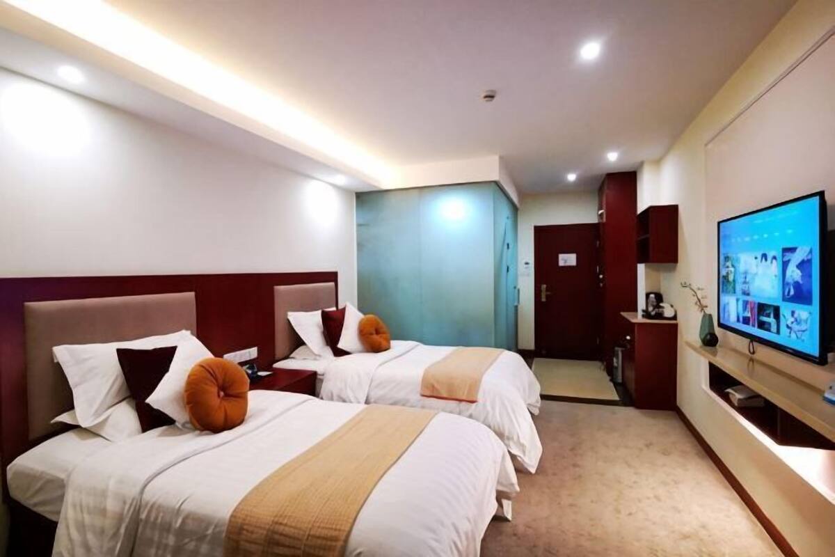 Een hotelkamer met twee bedden, een televisie, een bureau en een kledingkast.