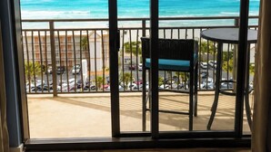 Ein Balkon mit Blick auf den Ozean, ein Korbstuhl und ein kleiner Tisch.