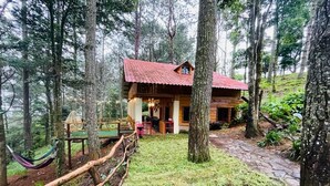 A rustic cabin with a red roof, surrounded by trees and a stone pathway. - Hotel y Cabañas La Posada del Cielo (La Palma)