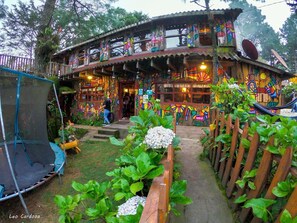A colorful, multi-level house with a porch and a trampoline in the yard.
