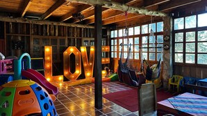 A cozy children's play area with a large illuminated 'LOVE' sign, wooden beams, and colorful play equipment. - Hotel y Cabañas La Posada del Cielo (La Palma)