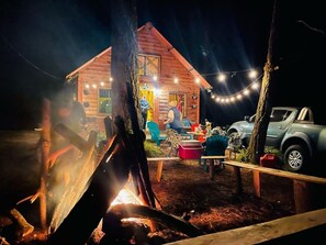 A rustic cabin with a fire pit, string lights, and outdoor seating. - Hotel y Cabañas La Posada del Cielo (La Palma)
