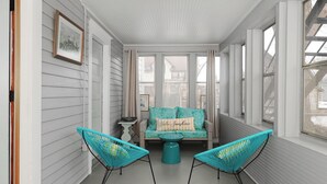 Une véranda aménagée avec un canapé, deux fauteuils et une petite table.