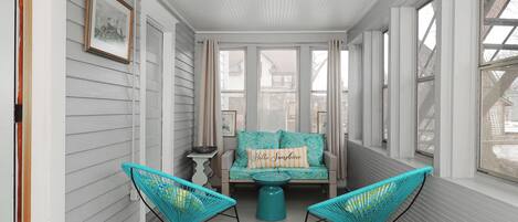 A sunroom with a sofa, two chairs, and a small table.