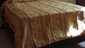 A bed with a patterned bedspread, a dark headboard, and two wall-mounted lamps.