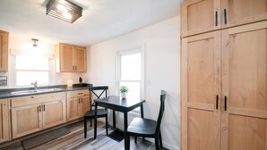 A kitchen with wooden cabinets, a black table, and a window.