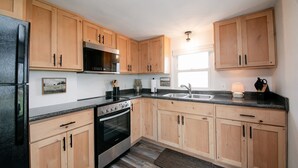 A modern kitchen with wooden cabinets, a stainless steel refrigerator, a built-in oven, a microwave, and a double sink.