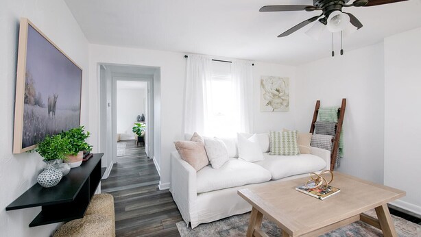 A modern living room with a white sofa, a wooden coffee table, and a black TV stand.