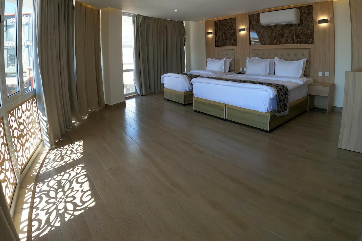 Una habitación de hotel espaciosa con una cama grande, un armario empotrado, un ventilador de techo y un amplio ventanal con cortinas.