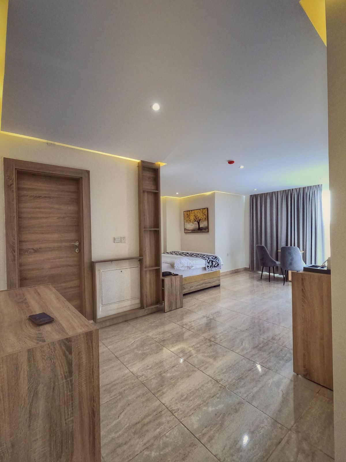 Quarto de hotel moderno com cama, escrivaninha, cadeira e uma pequena mesa.