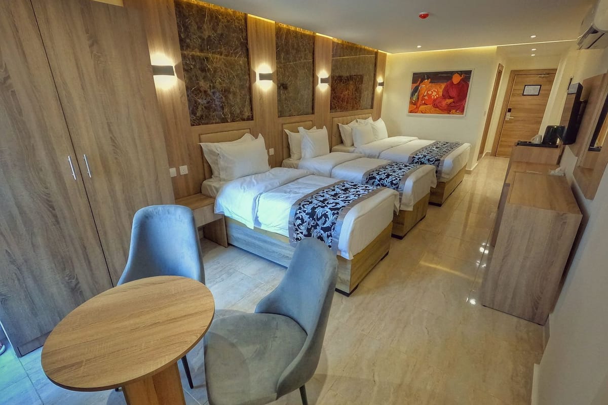 Una habitación de hotel con una cama grande, dos mesitas de noche, una pequeña mesa con dos sillas y un armario.