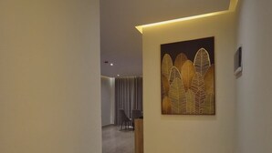 A modern hallway with a marble floor, a reception desk, and a decorative wall piece. - Grand Season hotel (Aqaba)