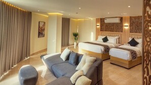 A modern hotel room with a large sofa, two beds, and a decorative wall panel. - Grand Season hotel (Aqaba)