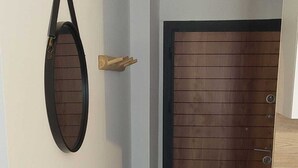 A hallway with a wooden door, a wall-mounted mirror, and a small wooden cabinet. - T2 seaside apartment - pianottoli-caldarello (Pianottoli-Caldarello)
