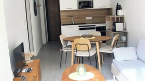A compact living space with a kitchenette, a dining area with a round table and chairs, a sofa, and a TV. - T2 seaside apartment - pianottoli-caldarello (Pianottoli-Caldarello)