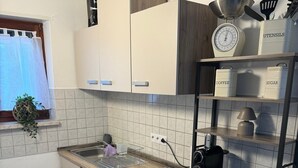 Una cocina compacta con horno integrado, cafetera y balanza sobre la encimera.