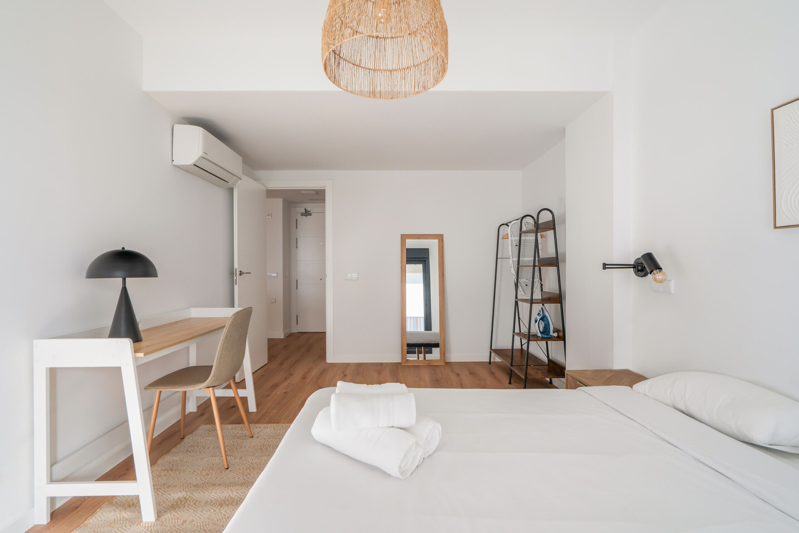 Una habitación de hotel moderna con una cama, un escritorio, una silla y un armario.