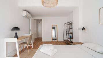 Una habitación de hotel moderna con una cama, un escritorio, una silla y un armario.
