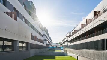 Un edificio moderno con un patio central, ventanas amplias y balcones.