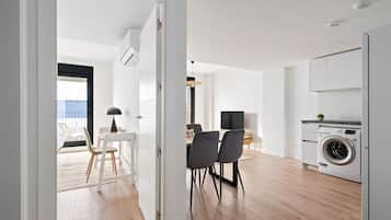 Una cocina moderna con lavadora, un comedor con sillas y un televisor.