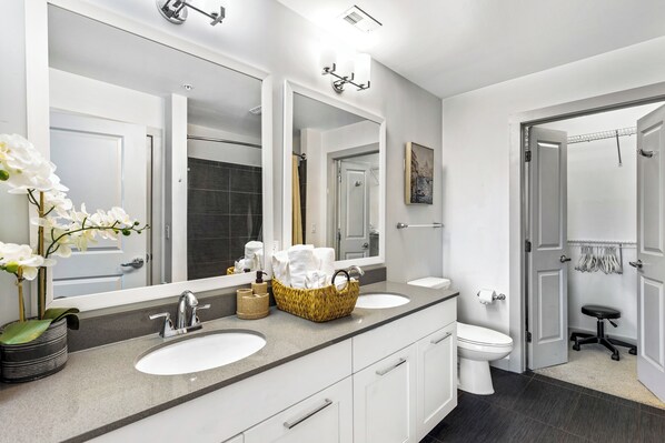 A modern bathroom with two sinks, a toilet, and a shower area.