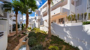 A modern building with multiple balconies, a small water feature, and lush greenery. - Casa Indalo (Mar de Pulpi) (San Juan de los terreros)