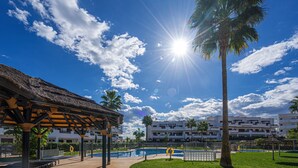 A sunny outdoor area with a pool, palm trees, and a building with multiple balconies. - Casa Indalo (Mar de Pulpi) (San Juan de los terreros)