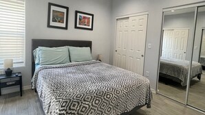 Une chambre à coucher comprenant un lit, une table de chevet, une armoire et deux tableaux encadrés accrochés au mur.