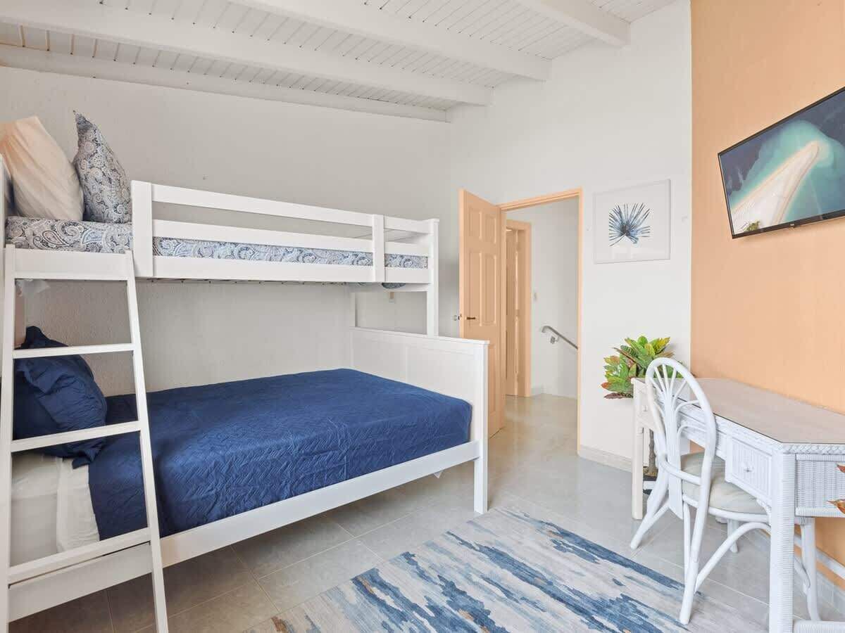 A room with bunk beds, a desk, and a chair.