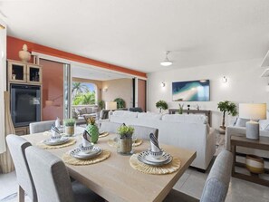 Ein moderner Essbereich mit einem Holztisch, gedeckt für vier Personen, umgeben von grauen Polsterstühlen.