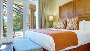 Hotelkamer met een groot bed, een bankje, een houten hoofdeinde en uitzicht op een zwembad door de glazen deuren.