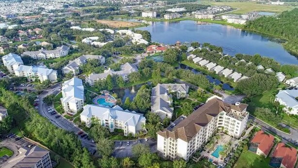 Luchtbeeld van een woongebied met huizen, een zwembad en een meer.