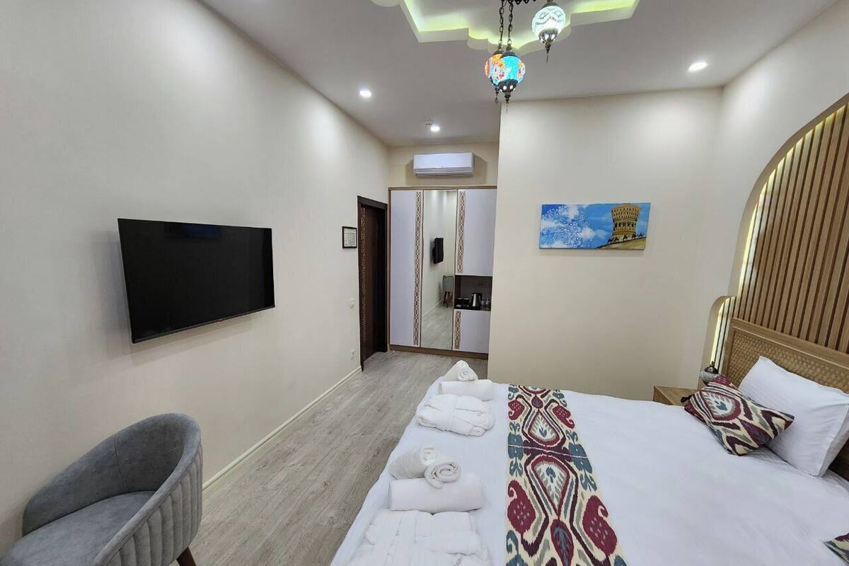 A hotel room with a bed, a TV, a chair, and a bathroom visible through an open door.