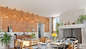 Un coin repas avec un mur en briques, des chaises en bois et une table dressée pour six personnes.