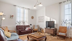 Un salon avec un canapé en cuir marron, une table basse en bois, un téléviseur et une chaise en bois.