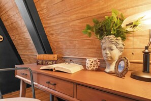 Ein Holztisch mit einer Büste, einem Blumentopf, einem Buch, einer Tasse und einer Lampe.