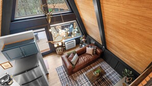Ein stilvolles Loft-Zimmer mit großem Fenster, einer braunen Ledersofa, einem Essbereich und einer Küche mit Edelstahl-Kühlschrank.