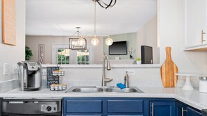 A modern kitchen with a stainless steel sink, a coffee maker, and a wooden cutting board. - Cozy 2BR Retreat + BBQ, WIFI & Parking (Raleigh)