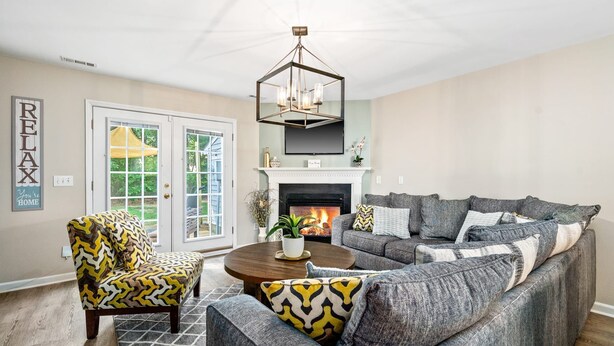 A living room with a fireplace, a sofa, a chair, and a coffee table. - Cozy 2BR Retreat + BBQ, WIFI & Parking (Raleigh)