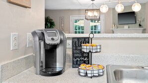 A kitchen with a coffee maker, a sign with a prayer for coffee, and a tray of coffee cups. - Cozy 2BR Retreat + BBQ, WIFI & Parking (Raleigh)