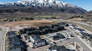A residential area with modern houses, a road, and a mountain range in the background. - Terrapin Basin R5939 | Ski Escape | Hot Tub & Desk (Mountain Green)