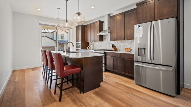 A modern kitchen with dark wooden cabinets, stainless steel appliances, and a central island with bar stools. - Terrapin Basin R5939 | Ski Escape | Hot Tub & Desk (Mountain Green)