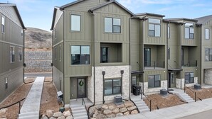 Un immeuble d’appartements moderne à plusieurs étages, doté de fondations en pierre, d’une entrée avec une porte et d’un petit espace porche.